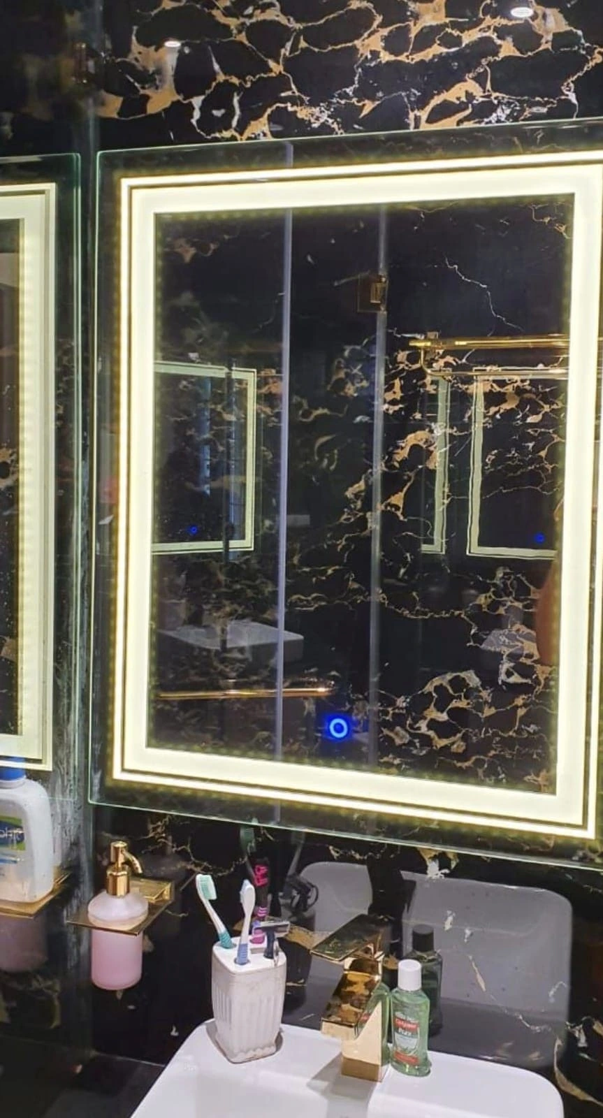 Custom rectangular LED mirror with warm lighting in a luxury black marble bathroom